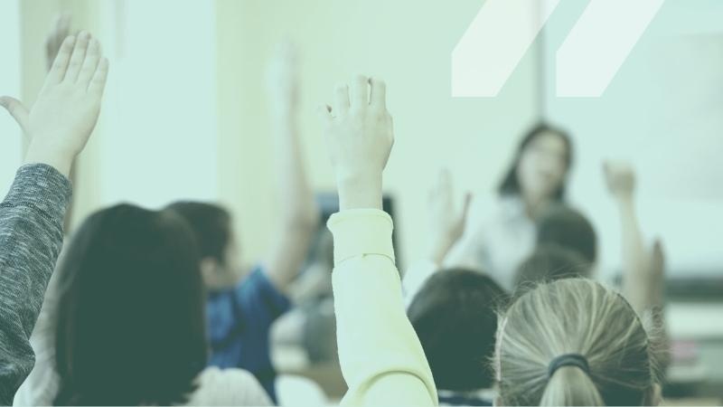 Image of students raising their hands in a classroom