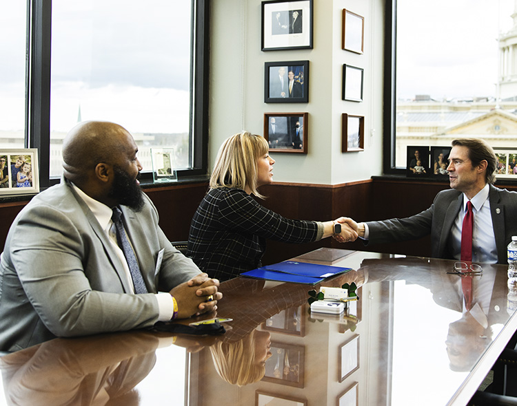 People shaking hands while sitting at a conference table